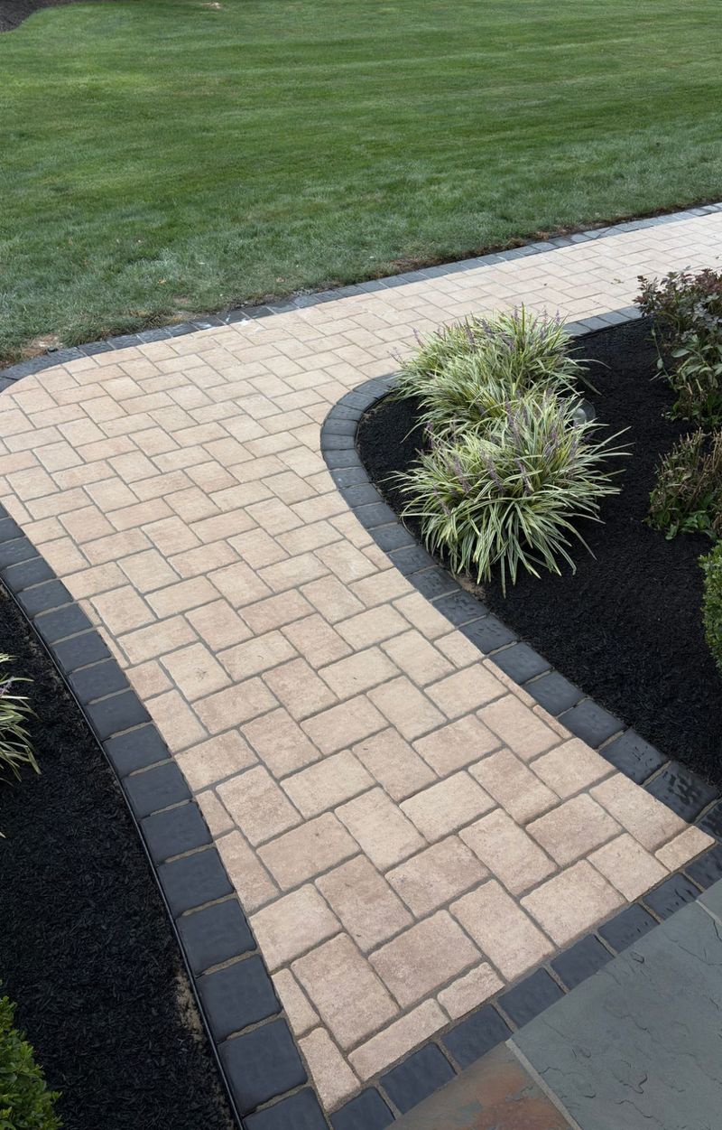 Curved paver walkway with a charcoal soldier border, sweeping past a black mulch bed of liriope