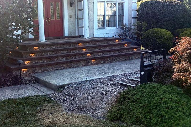 Stone veneer front steps with step lights glowing at dusk
