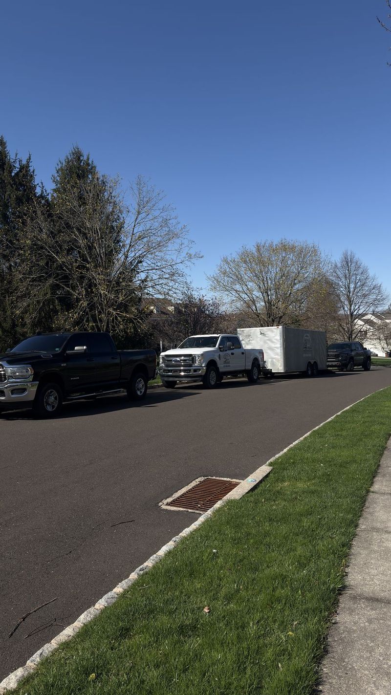 Hurtado's pickup trucks and enclosed trailer lined up on a neighborhood street